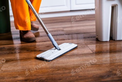 Preview: Woman washes laminate floor with professional flat mop. Housewife in orange pants cleans house