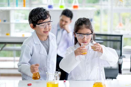 Preview: Little boy look to little girl pour some color chemical to flask in laboratory class room