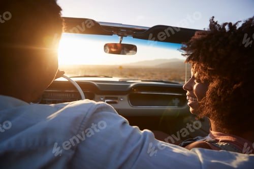 Preview: Rear View Of Couple On Road Trip Driving Classic Convertible Car Towards Sunset