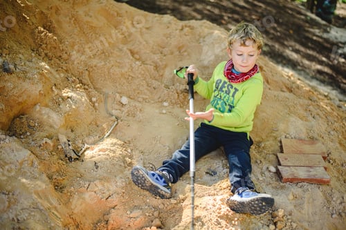 Preview: 5 year old blond boy playing on a mound of dirt without hygiene digging holes.