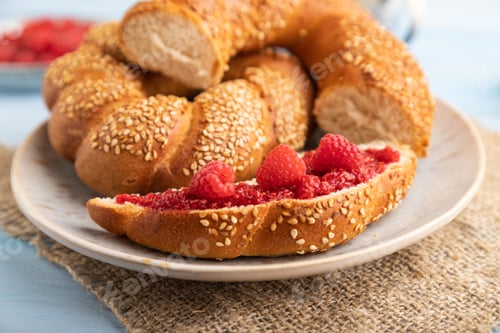 Preview: Homemade sweet bun with raspberry jam and cup of coffee on a blue wooden background and linen textil