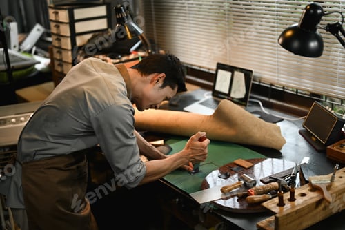 Preview: Concentrated male artisan cutting leather parts at table in his workshop