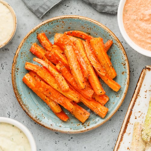 Preview: Baked season carrot sticks with sauce and hummus. Vegetarian healthy food. Flat lay, top view.
