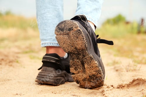 Preview: Fashion designer women's sneaker with high sole. Female sports black shoe on sand desert background.