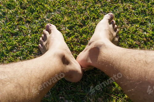 Preview: Man sitting on the grass with bare feet