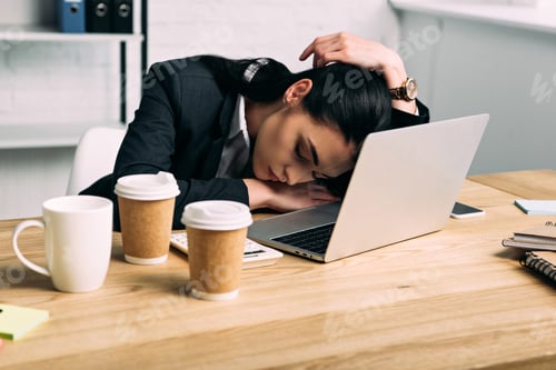 Preview: overworked businesswoman sleeping at workplace with laptop and coffee to go in office