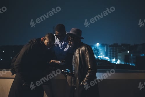 Preview: Three Men Looking at Phone at Night