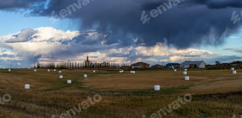 Preview: Panoramic view of farm fields with Hay Bales during a cloudy and stormy evening