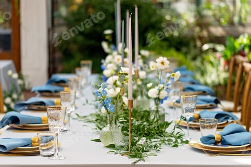 Preview: Banquet wedding table setting with blue napkins, gold cutlery, crystal, fresh flowers and candles.