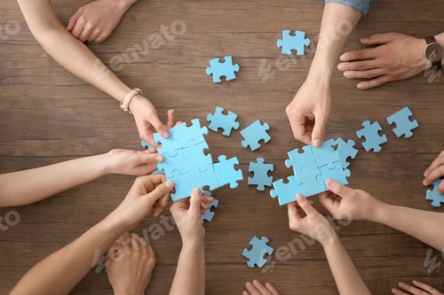 Preview: People with puzzle on wooden background, closeup of hands. Unity concept