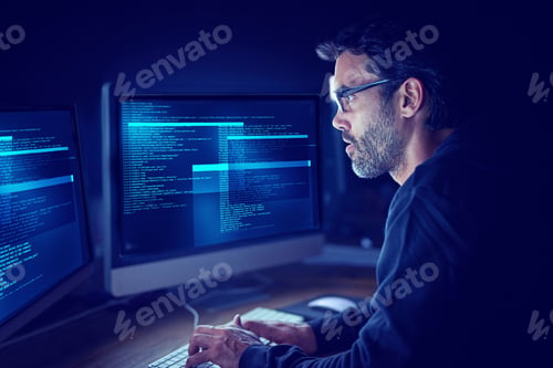 Preview: Immersed in the metadata. Shot of a focussed computer hacker using a computer in the dark.