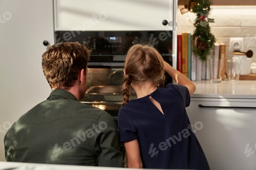 Preview: Back view of caucasian father and daughter waiting for homemade cookies