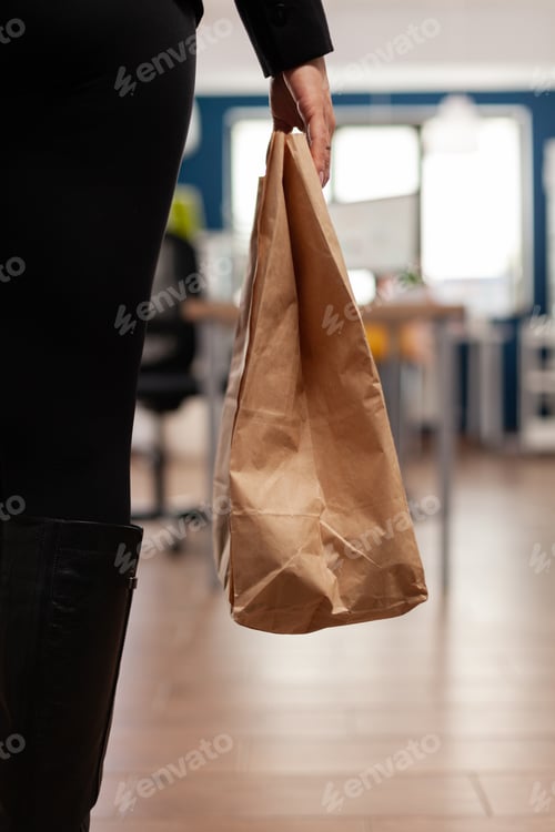 Preview: Businesswoman holding delivery takeaway food meal order paper bag during takeout lunchtime