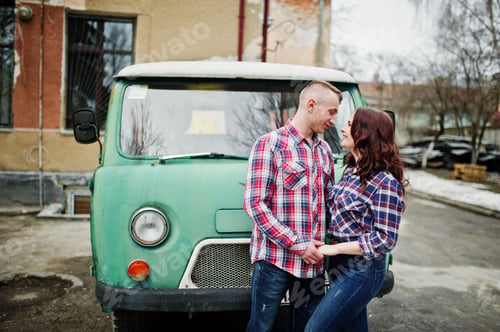 Preview: Stylish couple wear on checkered shirt in love together against old minivan.