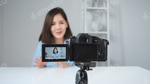 Preview: Happy smiling asian woman or beauty blogger with brush and camera recording video.