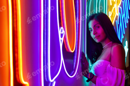 Preview: A woman standing against a neon light wall