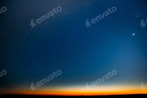 Preview: Night Starry Sky With Glowing Stars Above Countryside Field Landscape In Early Spring. Bright Glow