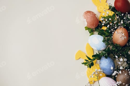 Preview: Stylish easter eggs, yellow bunny in nest of spring flowers