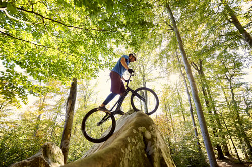 Preview: Male cyclist on trial bicycle on the top of boulder outdoors