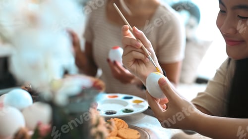Preview: Cheerful asian girl painting Easter eggs at home. Easter, holidays and people concept.