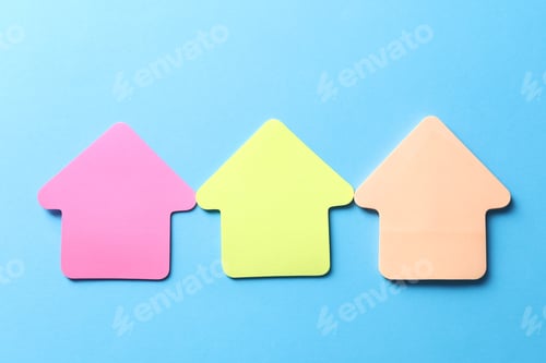 Preview: Colorful paper arrows on light blue background, flat lay