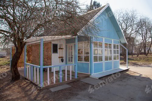 Preview: Country house cottage. Small wooden blue house in the garden. Shed. Garden tools - fork, shovel