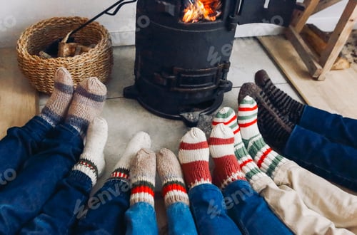 Preview: Big family wearing warm woolen socks warming feet by fireplace at cozy home in winter time