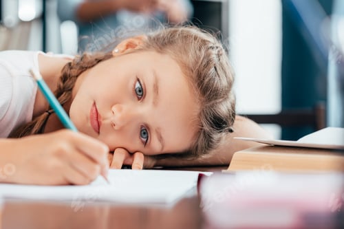 Preview: sad little girl writing homework