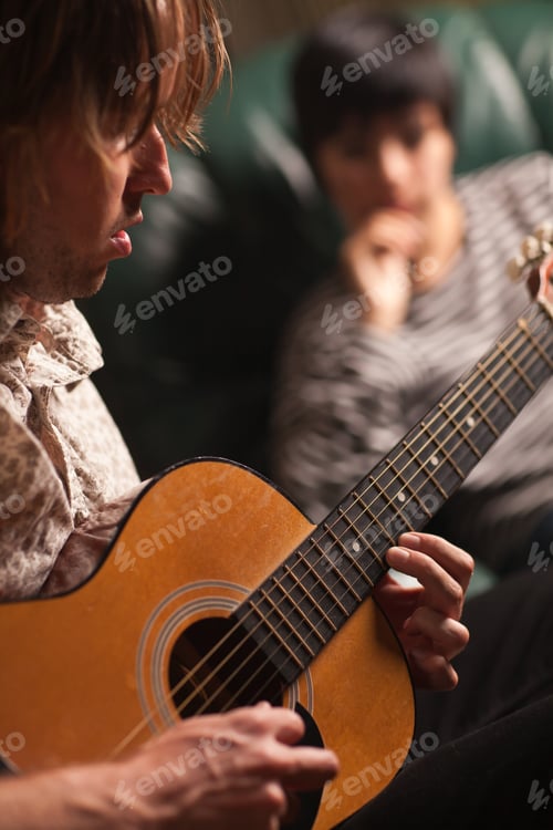 Preview: Young Musician Plays His Acoustic Guitar as Friend in the Background Listens.
