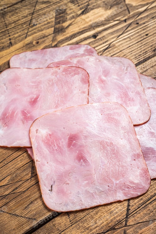 Preview: Square Slices of pork ham on wooden table. Wooden background. Top view