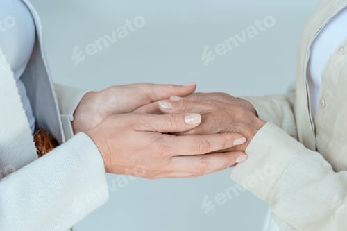 Preview: cropped view of mother and daughter holding hands isolated on grey