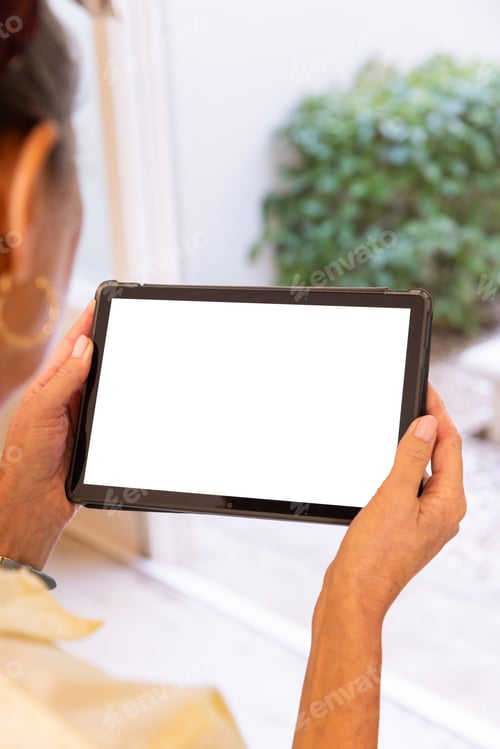 Preview: Holding tablet, woman viewing blank screen near window at home, copy space