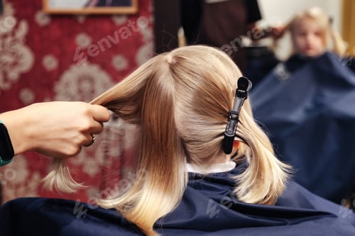 Preview: Hair salon, hairdresser makes hairdo for little girl in barber shop