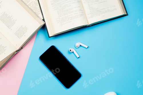 Preview: phone with earphones and open books on colored background. Audio book concept. modern education