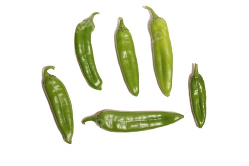 Preview: Vibrant collection of green chili peppers laid out on a white background.