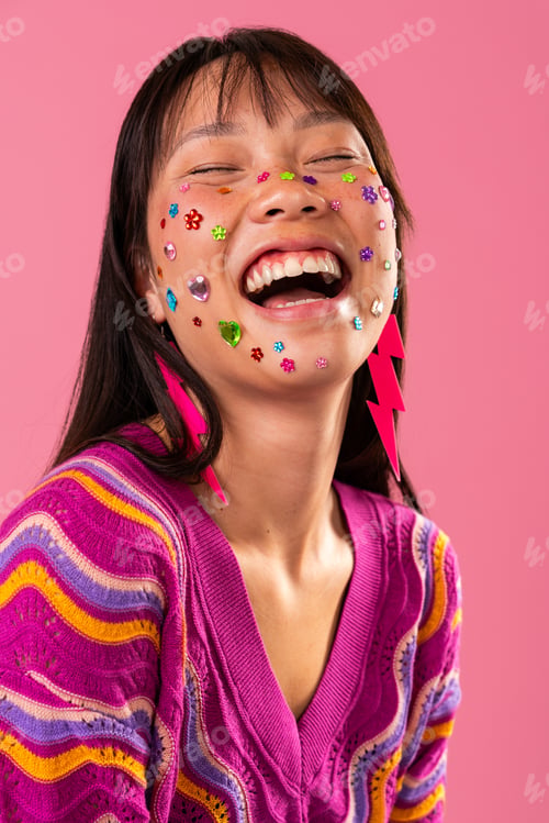 Vista previa: Beautiful asian woman portrait, asian woman laughing with face gems on pink background
