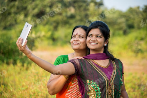 Preview: Mother and daughter taking a selfie with a smartphone in park.