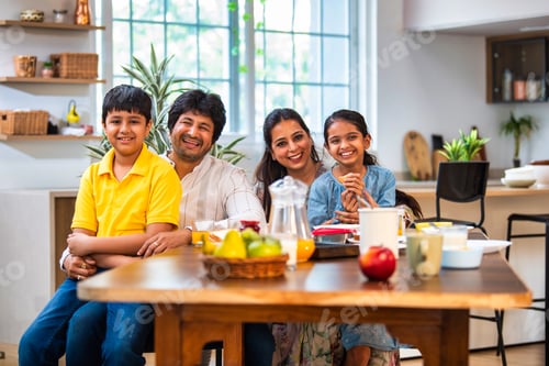 Preview: Happy Indian parents and kids share breakfast at the dining table, enjoying quality family time