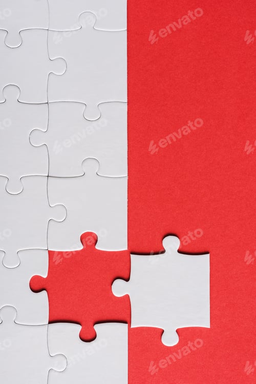 Preview: top view of incomplete jigsaw near white puzzle piece isolated on red