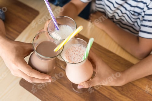 Preview: cropped shot of family clinking with glasses of milkshakes