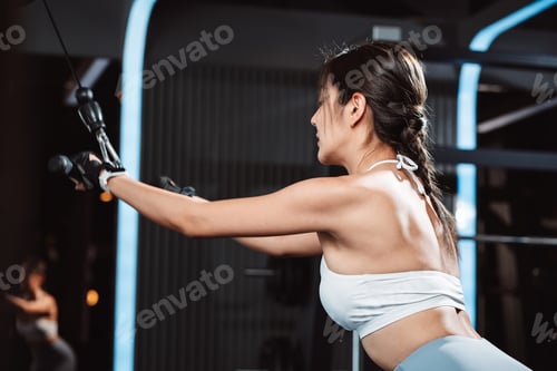 Preview: Women working out with weights training machine exercise lifting dumbbells at fitness gym.