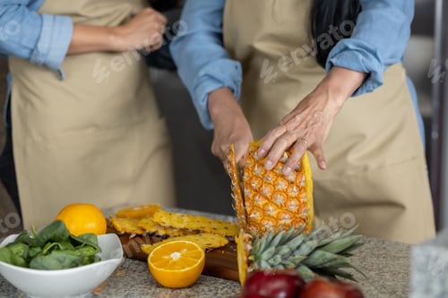 Preview: Close up of woman's hands cutting a pineapple