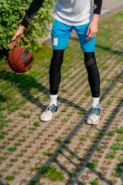 Preview: tall guy basketball player walks down the park path to the basketball court