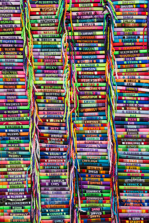 Preview: Brightly colored bracelets with embroidered names on a market stall.