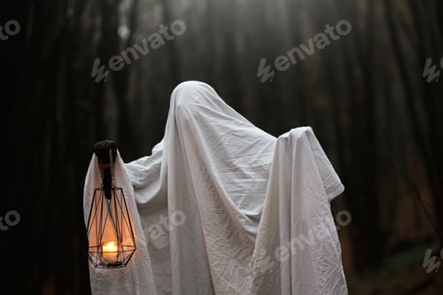 Preview: Happy Halloween! Spooky ghost holding glowing lantern in moody dark autumn forest