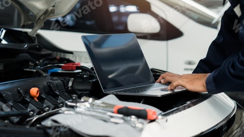 Preview: Car mechanic using laptop computer examining tuning fixing repairing car engine.
