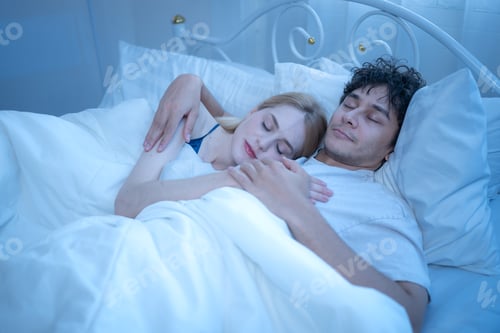 Preview: Loving couple cuddling peacefully in bed at night, showing warmth, affection