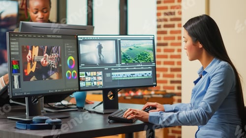 Preview: Asian filmmaker editing video and audio footage on multi monitors