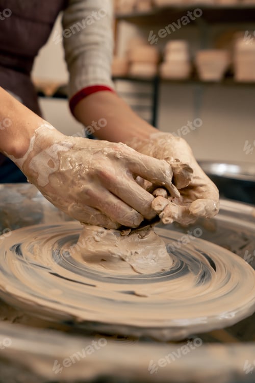 Preview: close up the clay modeling studio young girl hands giving shape to clay on a potter's wheel applied