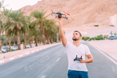 Preview: Young man holding drone before flight at nature